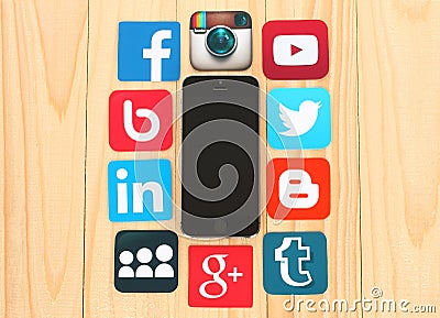 Famous social media icons around iPhone on wooden background Editorial Stock Photo