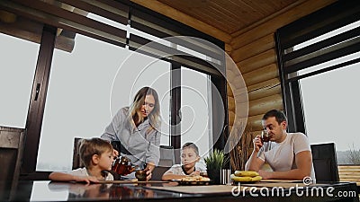 Família de quatro pessoas que come o café da manhã em sua cozinha com grande Windows Os povos estão sorrindo, os mães beijando e vídeos de arquivo Família de quatro pessoas que come o café da manhã em sua cozinha com grande Windows Os povos estão sorrindo, os mães beijando e vídeos de arquivo