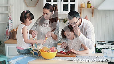 Família feliz que prepara o alimento na cozinha, cortando vegetais, movimento lento vídeos de arquivo Família feliz que prepara o alimento na cozinha, cortando vegetais, movimento lento vídeos de arquivo