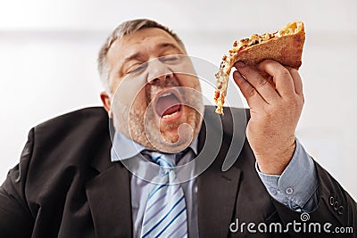 Fanatical obese man biting a slice of pizza Stock Photo