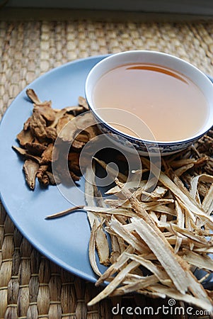 Bowl of brewed chinese herbs with dried assorted roots aside. Stock Photo