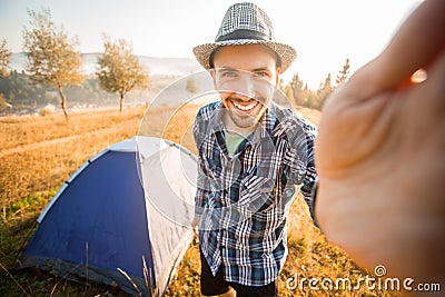 Fanny bearded man smiling and taking selfie in mountains from his smart phone. Stock Photo