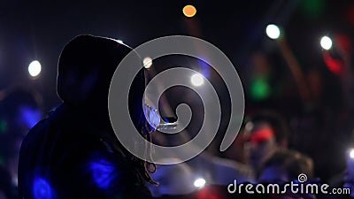 Fans Raise Hands and takes a photos in Front of Bright Colorful Strobing Lights at a concert in a night club. Stock Photo