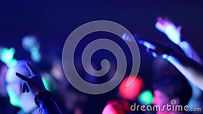 Fans Raise Hands and takes a photos in Front of Bright Colorful Strobing Lights on Stage. Stock Photo