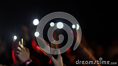 Fans Raise Hands and takes a photos in Front of Bright Colorful Strobing Lights on Stage. Stock Photo