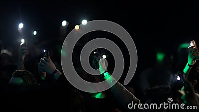 Fans Raise Hands and takes a photos in Front of Bright Colorful Strobing Lights on Stage. Stock Photo