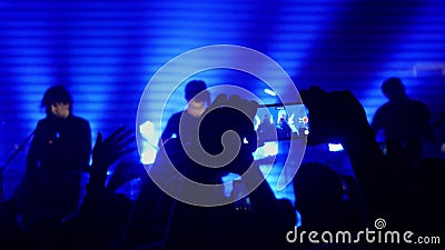 Fans waving their hands recording video and taking pictures with smart phones at music concert. People crowd partying at. Rock concert in a night club stock video footage Fans waving their hands recording video and taking pictures with smart phones at music concert. People crowd partying at. Rock concert in a night club stock video footage