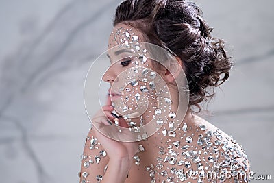 Fantastic fashion portrait of a young beautiful woman with transparent crystals on her face and shoulders. Stock Photo