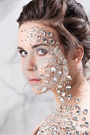 Fantastic fashion portrait of a young beautiful woman with transparent crystals on her face and shoulders. Stock Photo