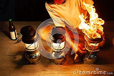 Fantastic fire flames, the old man with three vintage kerosene pressure lanterns on wooden at night, beautiful brightly burning Editorial Stock Photo