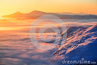 Fantastic scenery with the high mountains in snow, dense textured fog and a sunrise in the cold winter day. Stock Photo