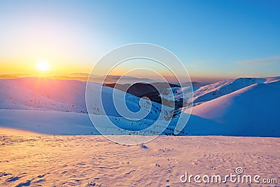 Fantastic scenery with the high mountains in snow and a sunrise in the cold winter day. Stock Photo