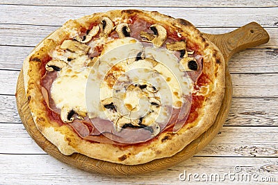 Fantastic thin crust pizza with prosciutto, funghi and gratin mozzarella cheese on wooden board Stock Photo