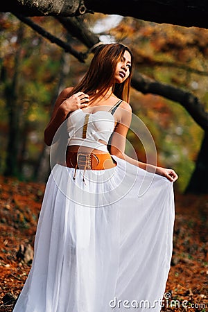 Fantastic young woman. beautiful fantasy girl fairy with white long dress in windy autumn park Stock Photo