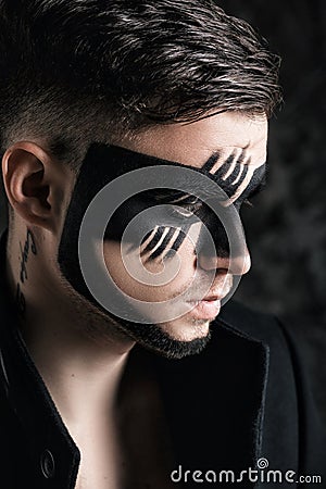 Fantasy art makeup. man with black painted mask on face. Close up Portrait. Professional Fashion Makeup. Stock Photo