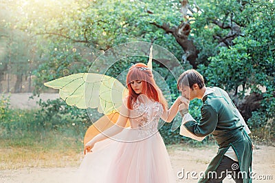 fantasy couple together. Fairy man groom elf Prince kisses hand of woman bride pixie. Themed wedding. Red hair girl Stock Photo