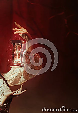 Fantasy photo levitation. Close-up female hands hold a magic hourglass bright white light, sparkles. Time control and Stock Photo