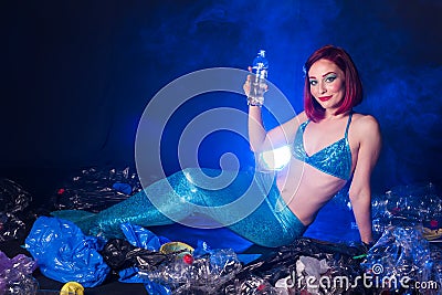 Fantasy stupid mermaid in deep ocean. Plastic trash and bottles pollution in ocean. Ecocatastrophe, garbage and plastic Stock Photo