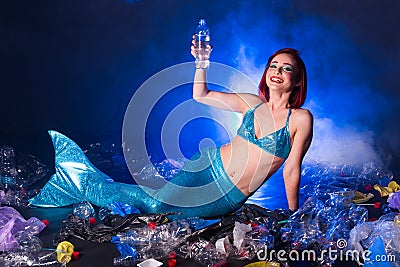 Fantasy stupid mermaid in deep ocean. Plastic water bottles and bags pollution on sea floor. Environmental problem. Stock Photo