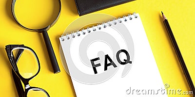 FAQ on a notebook with glasses, magnifier and pensil Stock Photo