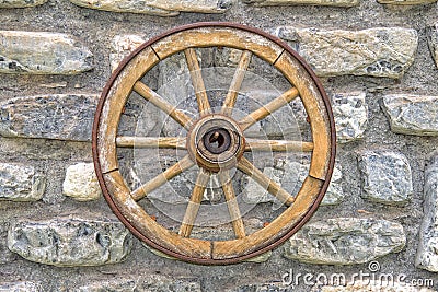 Far west wagon wheel on stone wall Stock Photo