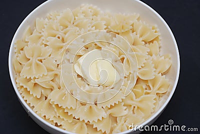 Farfalle Pasta in Bowl with Butter Close Up over Blue Background. Stock Photo