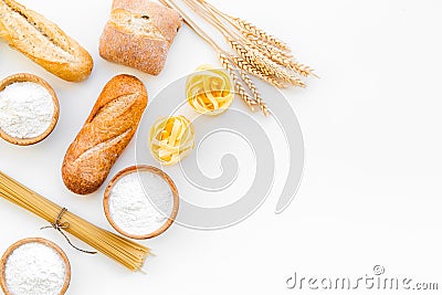 Farinaceous food. Fresh bread and raw pasta near flour in bowl and wheat ears on white background top view space for Stock Photo