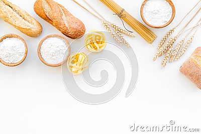 Farinaceous food. Fresh bread and raw pasta near flour in bowl and wheat ears on white background top view space for Stock Photo