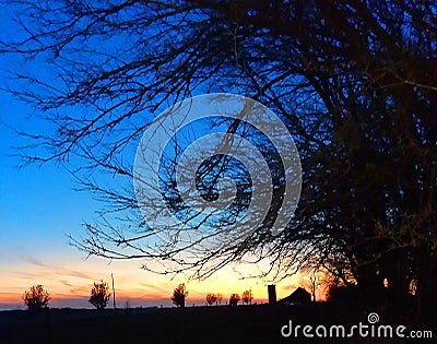 A farm as the sunset takes over while the deepblue high above. Stock Photo