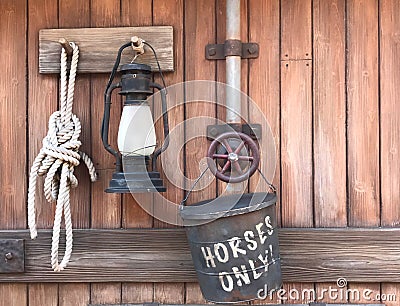 Farm tools rope, lamp, horse bucket hanging on wooden wall - r Stock Photo