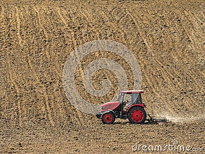 Farm tractor harrowing arable field Stock Photo