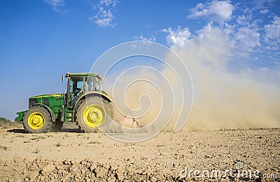 Farm tractor preparing dusty soil affected by drought Editorial Stock Photo