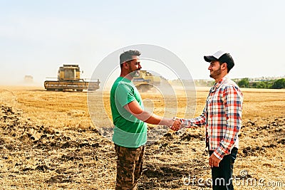 Farmer and agronomist shaking hands standing in a wheat field after agreement. Agriculture business contract concept Stock Photo