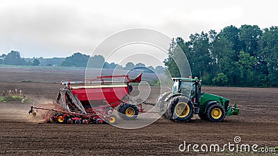 The farmer in the autumn treats the fields with the tractor and enriches them with mineral fertilizers. Editorial Stock Photo