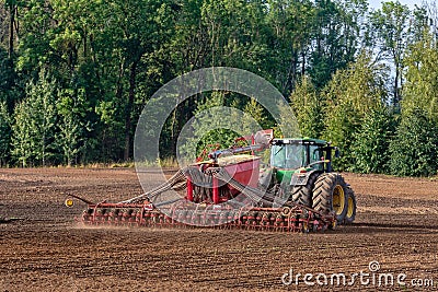 The farmer in the autumn treats the fields with the tractor and enriches them with mineral fertilizers. Editorial Stock Photo