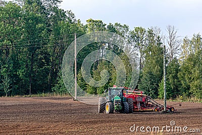 The farmer in the autumn treats the fields with the tractor and enriches them with mineral fertilizers. Editorial Stock Photo