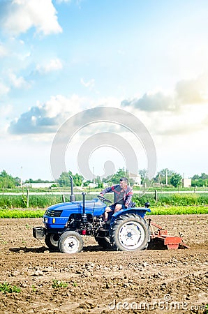 The farmer drives a tractor with a milling unit equipment. Loosening land cultivation Use of agricultural machinery to speed up Stock Photo