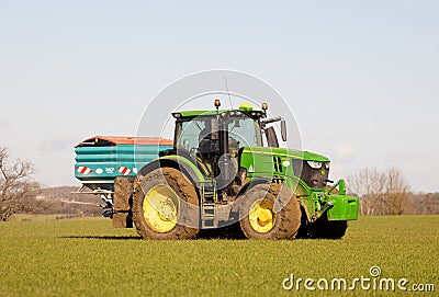 Farmer driving a tractor and sprinkling fertiliser on a field. Editorial Stock Photo