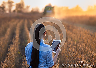 Farmer girl with tablet and combine harvester Stock Photo