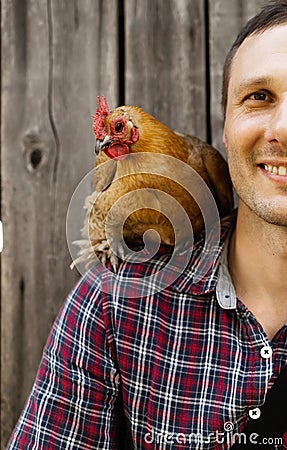 The farmer hugs a chicken. pleasant man is hugging a cock. close up shot emotions. Stock Photo