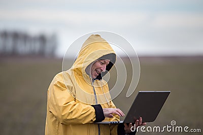 Farmer with laptop in field on cold day Stock Photo