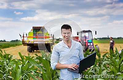 Farmer with laptop during harvest Stock Photo