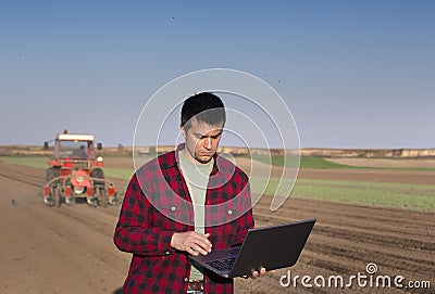 Farmer with laptop and tractor sowing Stock Photo