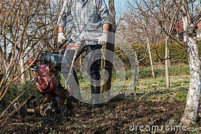 Farmer performing garden soil tillage with old poor cultivator tiller agricultural machine Stock Photo