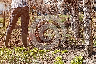 Farmer performing garden soil tillage with old poor cultivator tiller agricultural machine Stock Photo