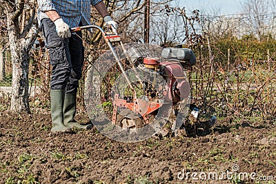 Farmer performing garden soil tillage with old poor cultivator tiller agricultural machine Stock Photo