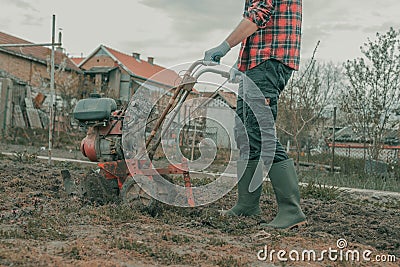 Farmer performing garden tillage with an old motor cultivator Stock Photo