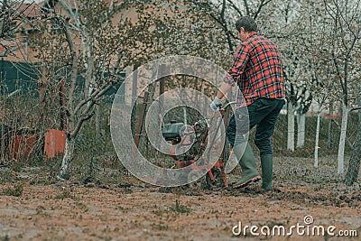 Farmer performing garden tillage with an old motor cultivator Stock Photo