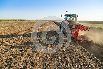 Farmer plowing stubble field with red tractor Stock Photo