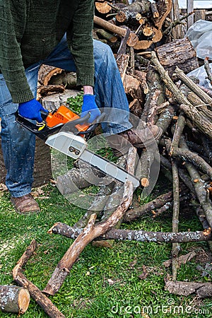 Farmer sawing a log with a chainsaw Stock Photo